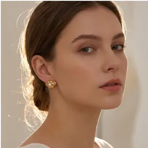 Dettaglio di orecchini dorati a forma di labbra con perla su modella in stile minimalista.