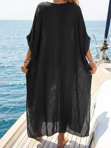 Back view of a loose black maxi beach cover-up dress on a sunny yacht wooden deck.