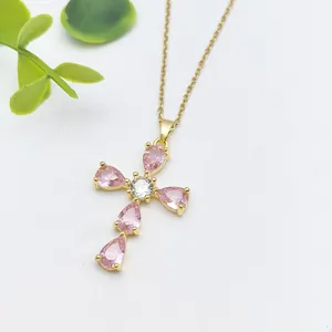 Collana a croce dorata con zirconi rosa a goccia e pietra centrale su una catena sottile
