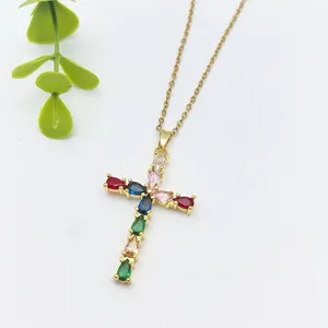 Collana a croce dorata con zirconi colorati a forma di goccia su sfondo bianco