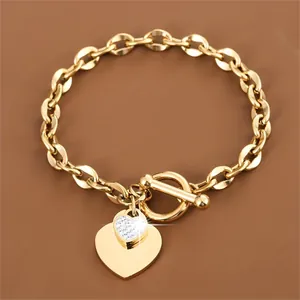 Detail of a gold-colored heart pendant bracelet with a stylish OT toggle clasp.