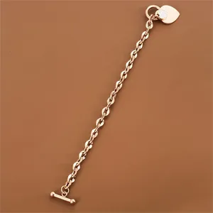 Detail view of rose gold titanium steel chunky chain bracelet with heart charm and OT clasp