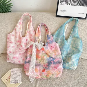 Set of three floral lace tote bags in pink, colorful, and blue shown on a sofa