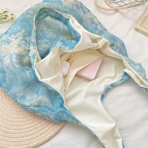 Detail view of the spacious interior and zipper pocket of a blue floral lace tote