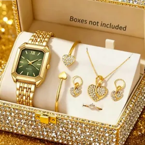 Detail of gold luxury jewelry set including green dial watch and heart accessories.