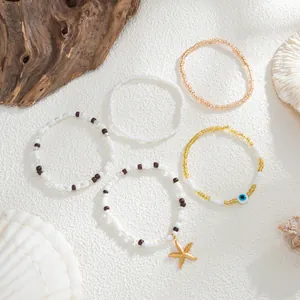 Detail of five beach-themed beaded bracelets with starfish and evil eye charms