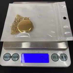 Stainless steel circular locket necklace weighing 9.4 grams on digital scale.