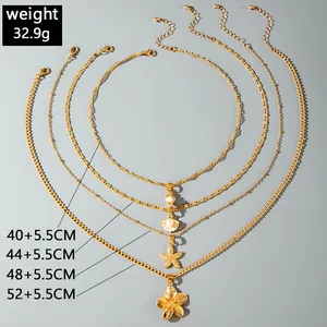 Detail of layered gold-tone necklace with starfish and flower charms, showing sizes