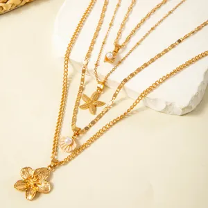 Close-up of gold-layered necklaces with starfish, flower, and pearl shell pendants