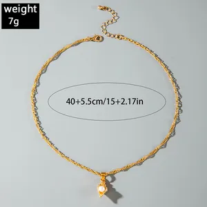 Detailed view of gold twisted chain necklace with pearl shell pendant and weight