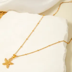 Detailed view of gold starfish pendant necklace on beaded chain for summer beach fashion