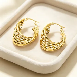 Gros plan sur la texture métallique torsadée dorée de ces boucles d'oreilles créoles en U
