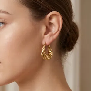 Vue détaillée d'élégantes boucles d'oreilles créoles torsadées en U dorées sur modèle