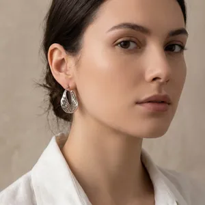 Détail rapproché d'élégantes boucles d'oreilles créoles en U avec motif ondulé
