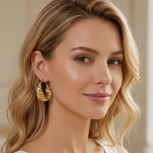 Boucles d'oreilles dorées en forme de U avec motif torsadé portées par un mannequin.