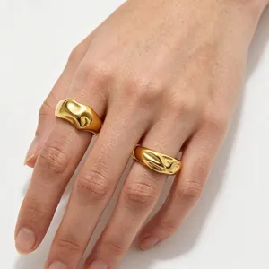Detailed view of golden irregular textured bubble rings worn on a woman's hand fingers