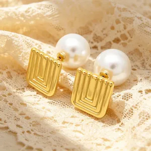 Detailed view of golden geometric square earrings with a large white pearl inlay