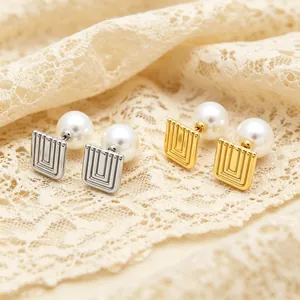 Close-up of geometric square earrings with white pearls and ridged metal design