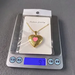 Gold stainless steel heart locket necklace with pink center on a scale, weight 9.7g