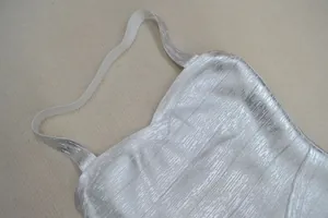 Gros plan du tissu métallique argenté et des bretelles élastiques de la robe bandage