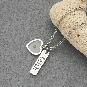 Close-up detail of stainless steel necklace with heart mustard seed and 'faith' engraved bar