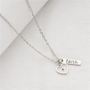 Detailed close-up of a stainless steel faith necklace with a heart and mustard seed.