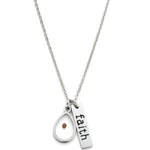 Detailed close-up of the mustard seed waterdrop pendant and faith engraved bar necklace
