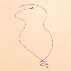 Macro shot of stainless steel necklace with engraved faith bar and heart pendant