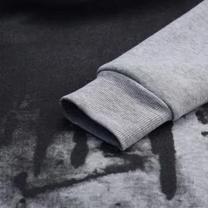 Close-up of grey ribbed cuff and splash ink print on black men's hoodie detail view