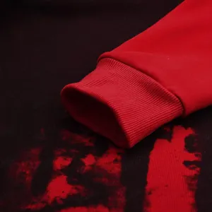Detailed macro view of red ribbed cuff on men's splash ink print hooded sweatshirt