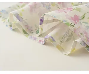 Détail en gros plan de l'ourlet floral fluide d'une robe d'été légère pour fille.