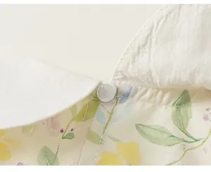 Détail macro d'une robe fleurie pour fille avec col Claudine blanc et bouton