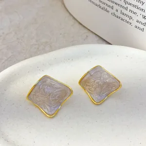 Macro detail view of vintage-style geometric gold-plated square enamel stud earrings