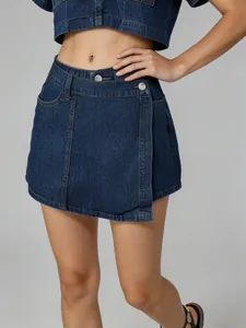 Detailed view of the irregular hem and silver buttons on this dark denim skort