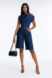 Le mannequin porte une combinaison en jean asymétrique et un petit sac à main noir