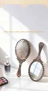 Detailed view of an ornate vintage handheld makeup mirror with intricate floral carvings