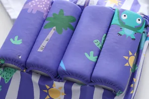 Gros plan sur les blocs de flottabilité d'un maillot de bain violet pour garçon avec dinosaures.