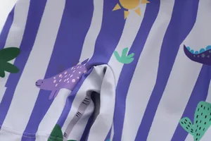 Gros plan sur le tissu du maillot de bain enfant avec imprimé dinosaure et rayures