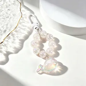 Macro view of a translucent iridescent whale keychain with decorative pearlescent beads