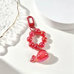Detailed view of a red translucent whale keychain with glossy beads and metal clasp