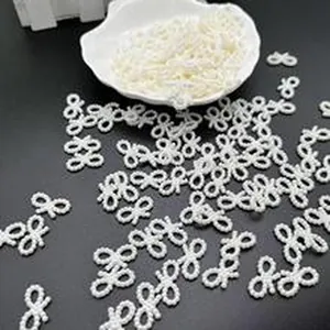 Close-up of white bow-shaped imitation pearl charms for DIY jewelry making