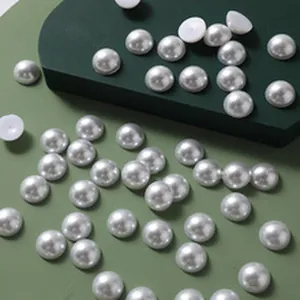 Close-up of scattered white half-round ABS imitation pearls for DIY jewelry making.