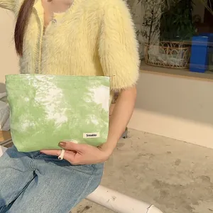 Portable green tie-dye canvas cosmetic bag for women shown in lifestyle setting