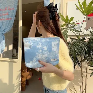 Stylish blue and white tie-dye canvas makeup bag held in hand for a lifestyle showcase