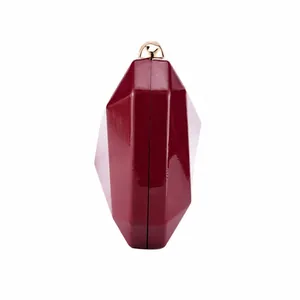 Detailed side view of a glossy burgundy geometric evening clutch bag with gold clasp