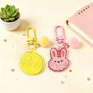 Close-up detail of cute pink rabbit and yellow circle acrylic keychains with frosted charms