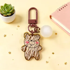 Macro view of cartoon bear acrylic keychain with white ball charm and brown clip