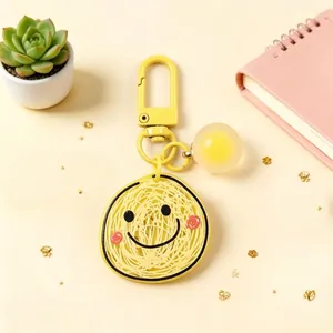 Close-up view of a cute yellow smiley face keychain with a unique thread pattern