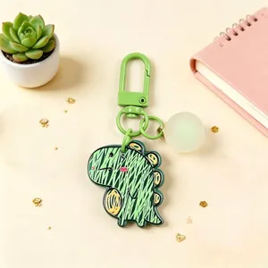 Detailed view of a green acrylic cartoon dinosaur keychain with a luminous ball accessory