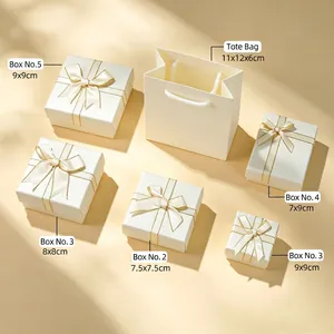 Detailed view of cream jewelry gift box set in various sizes with gold ribbon bows
